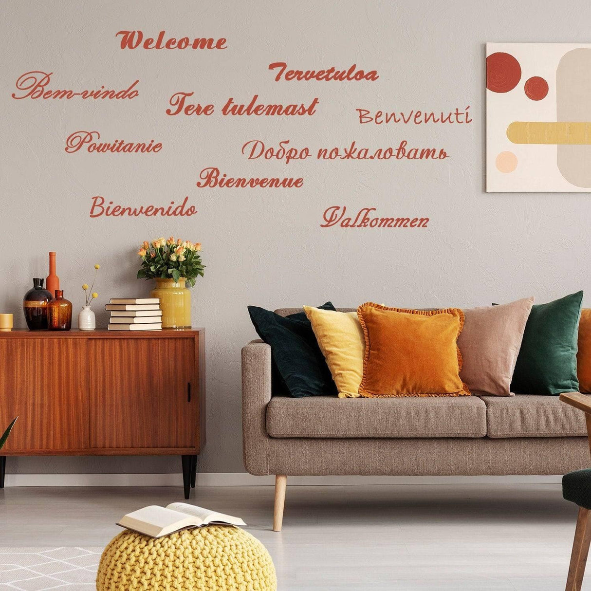 Living room with colorful pillows and welcoming wall decals in multiple languages.