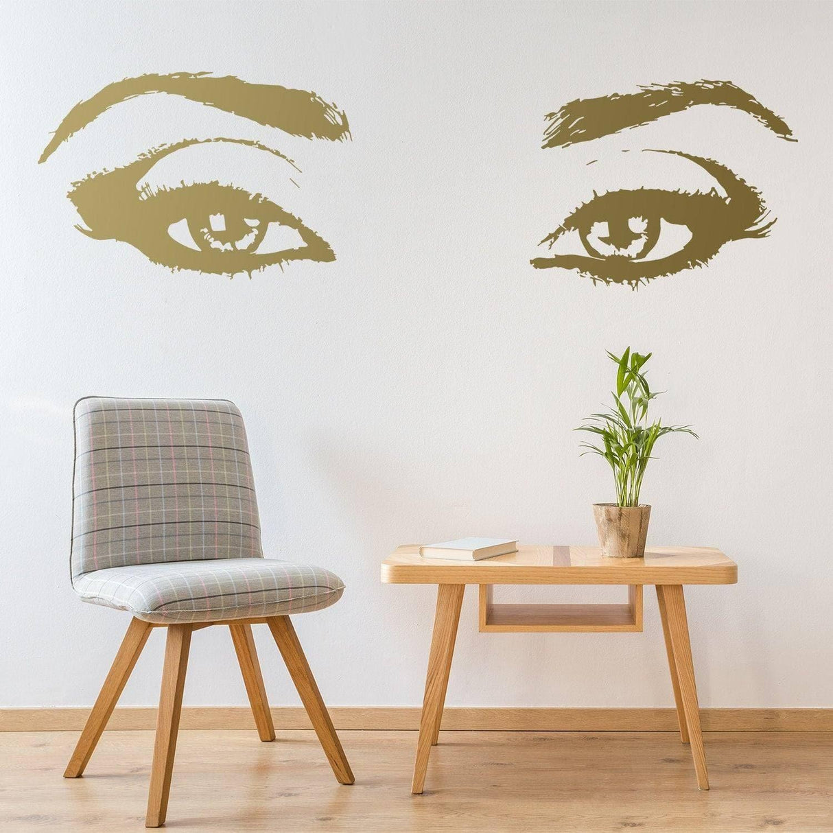 Elegant wall decal featuring golden eyelash silhouettes above a stylish chair and table in a modern room.