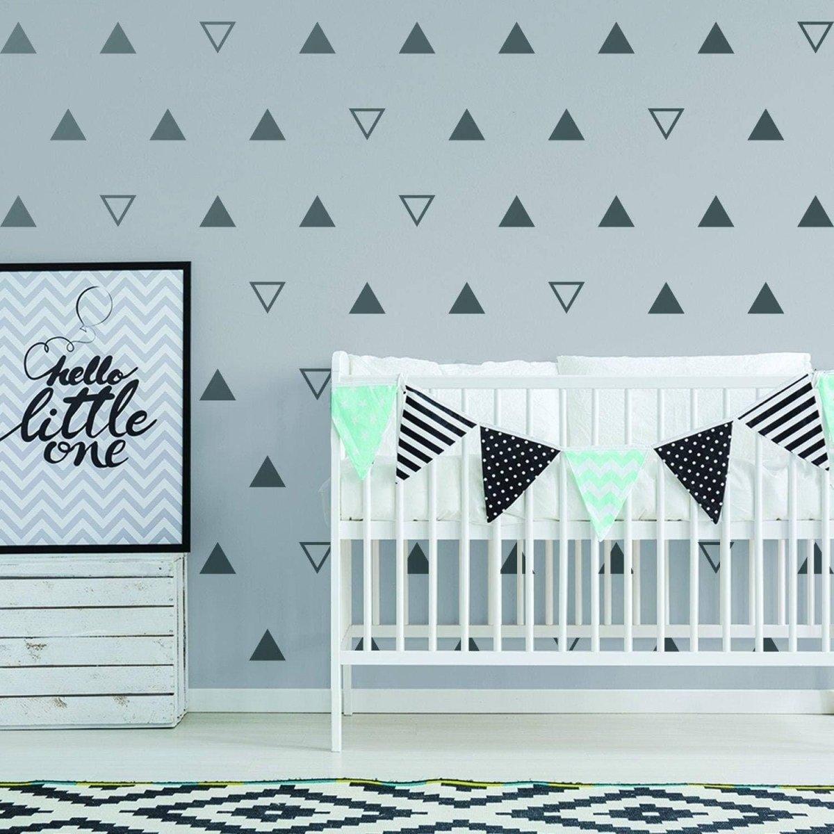 Stylish nursery featuring geometric triangle wall decals, a crib, and decorative bunting for a charming kids' room.