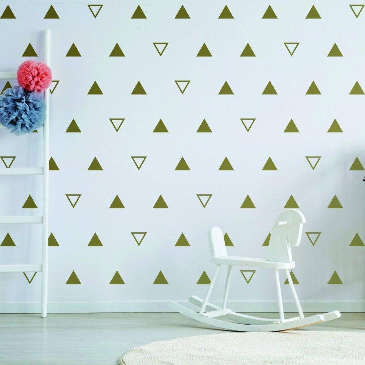 Geometric triangle wall decals in soft gold on white nursery wall with rocking chair and ladder.