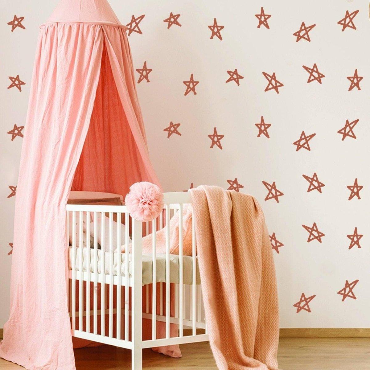 Baby nursery decorated with rose-colored star decals and a cozy crib, perfect for a magical baby shower theme.