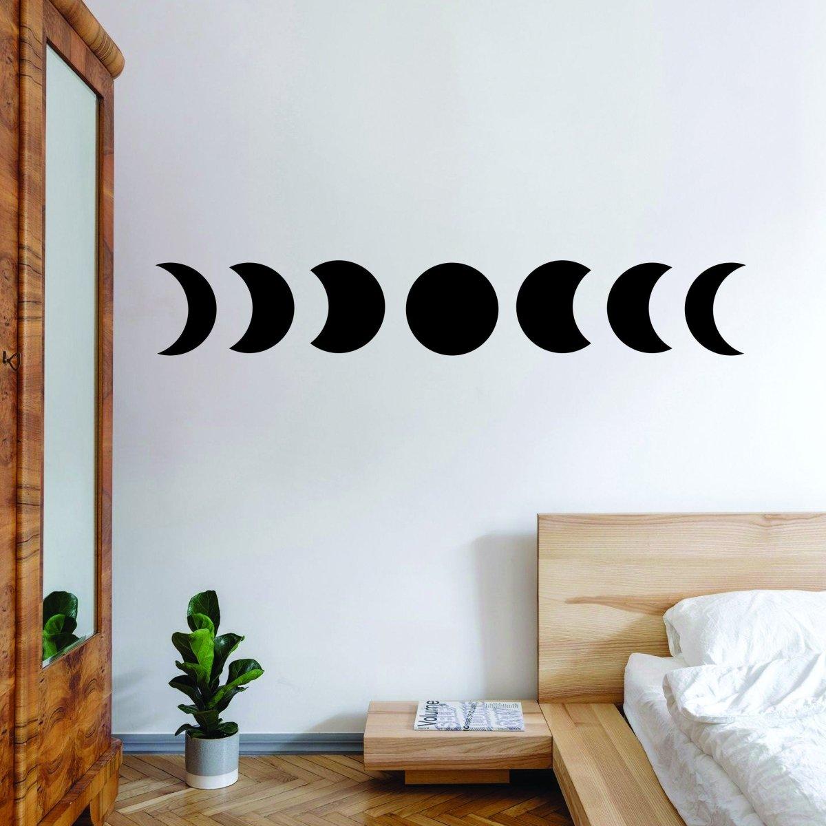 Moon phase wall hanging decor in modern bedroom, featuring black vinyl stickers on a white wall.