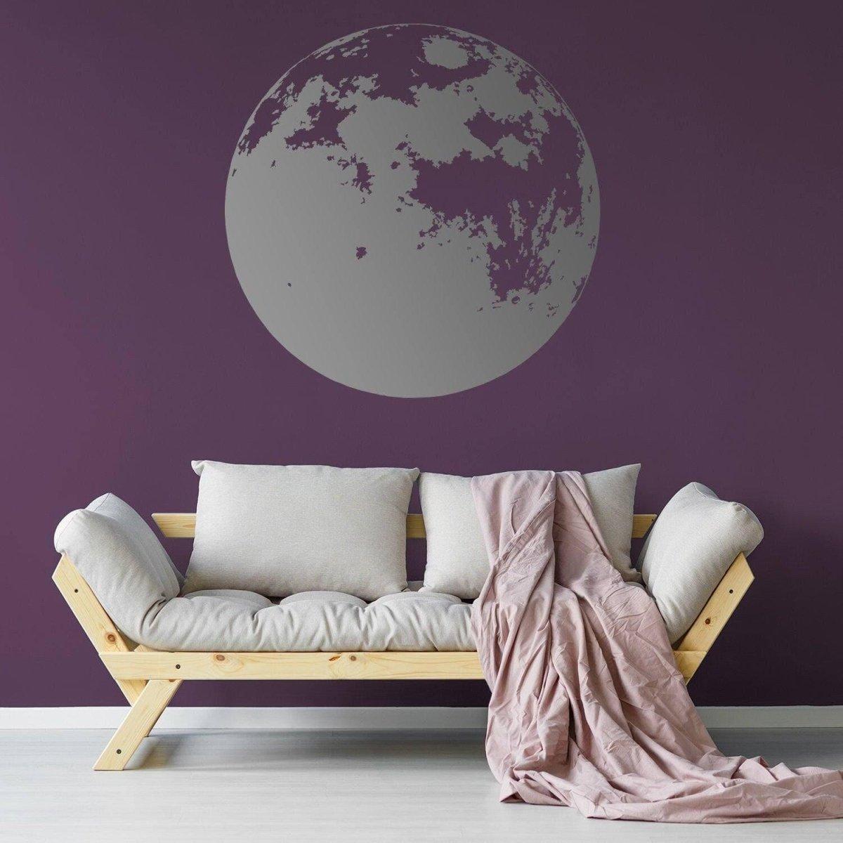 Moon phase wall decal on a dark purple wall with a cozy sofa and blanket, perfect for nursery decor.