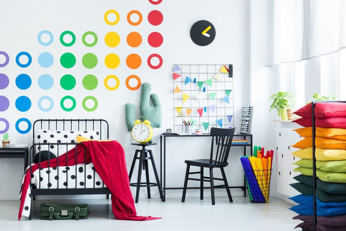Vibrant circle wall decals in a colorful room with a bed, desk, and rainbow pillows for whimsical decor.