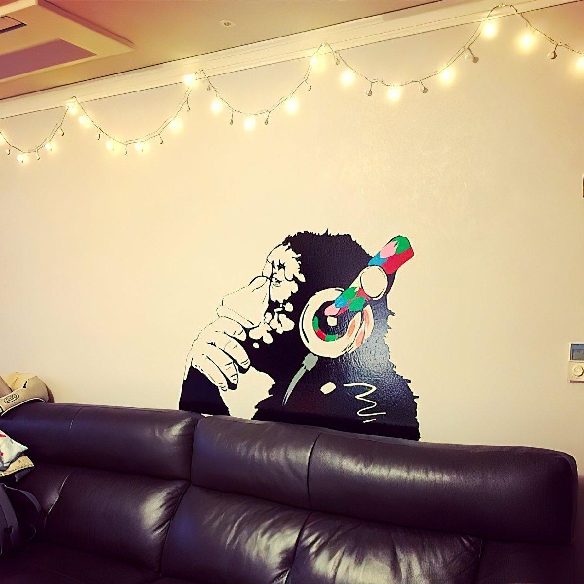 Contemplative monkey wall decal with headphones, perfect for kids' room decoration and music lovers.
