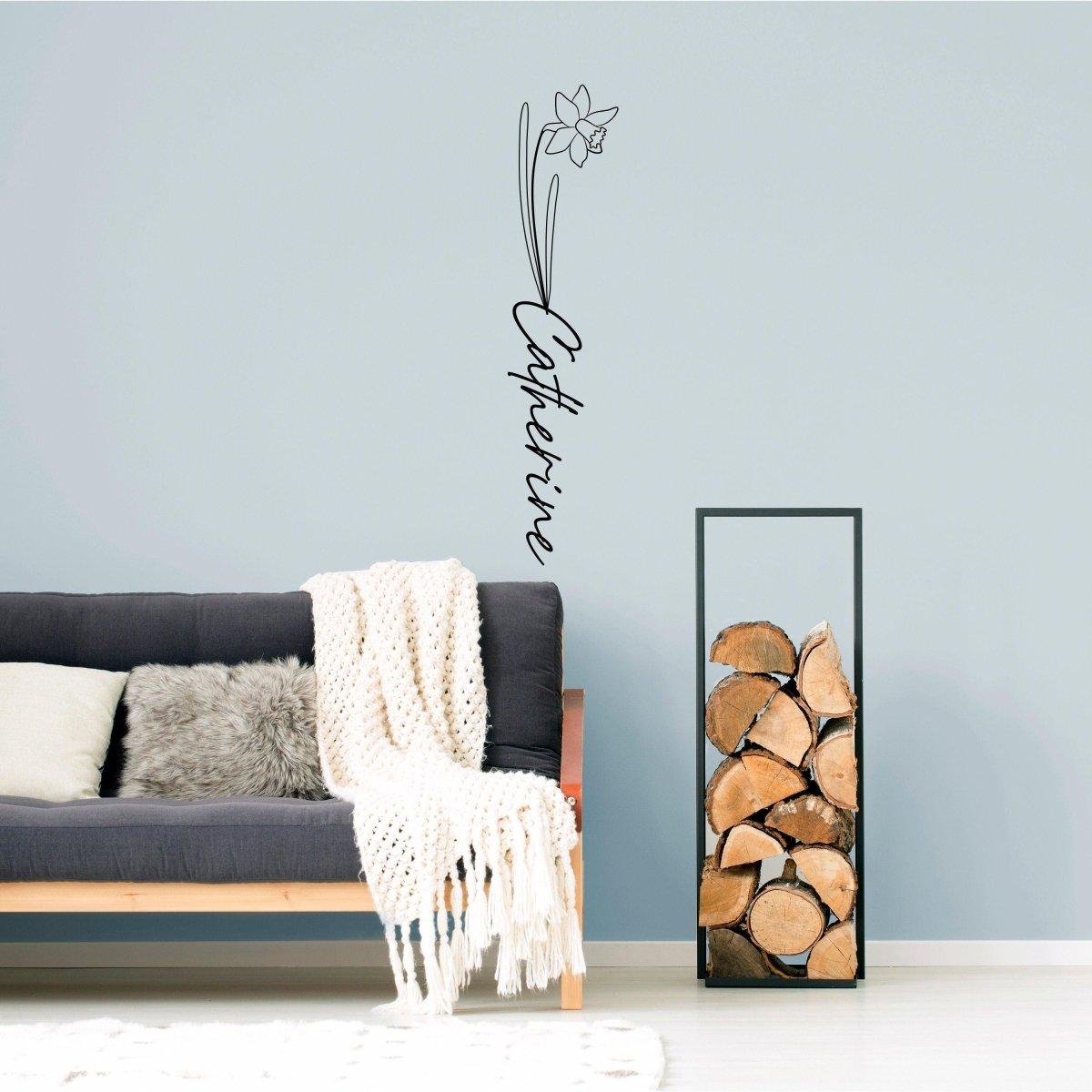 Personalized flower name decal on wall above modern couch, featuring custom name design with floral accents.