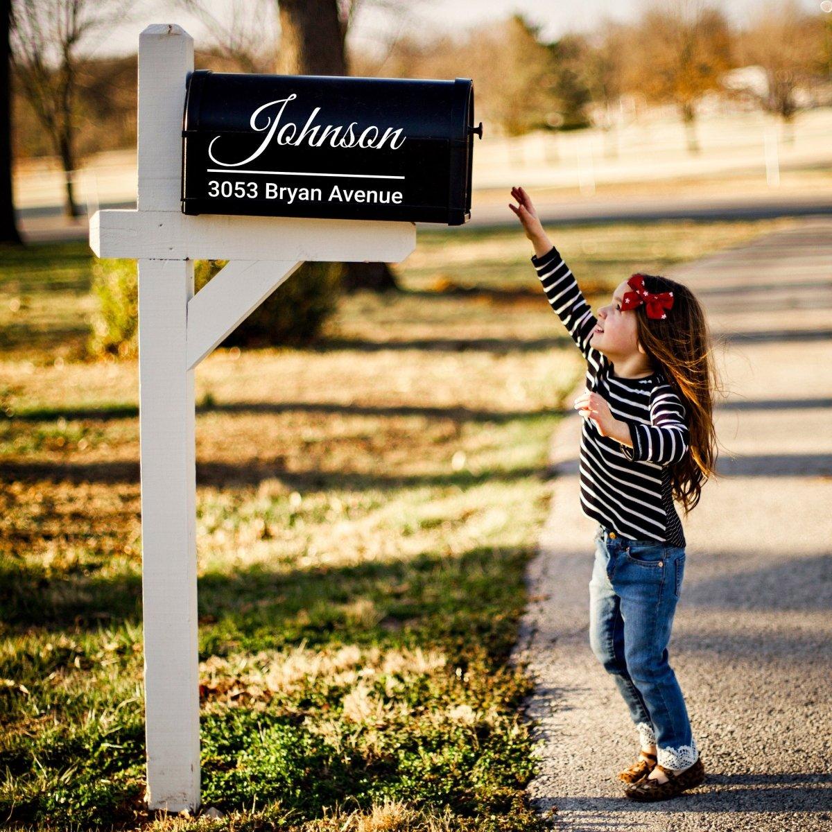 Little girl reaching for a personalized mailbox with custom address decal on a sunny day.