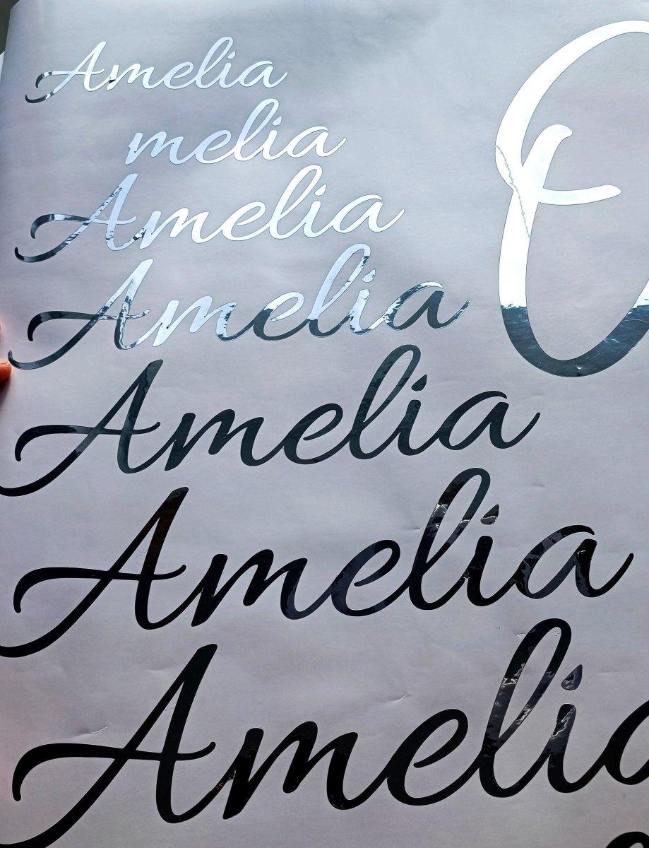 Customizable silver vinyl name decals showing variations of the name 'Amelia' in different fonts.