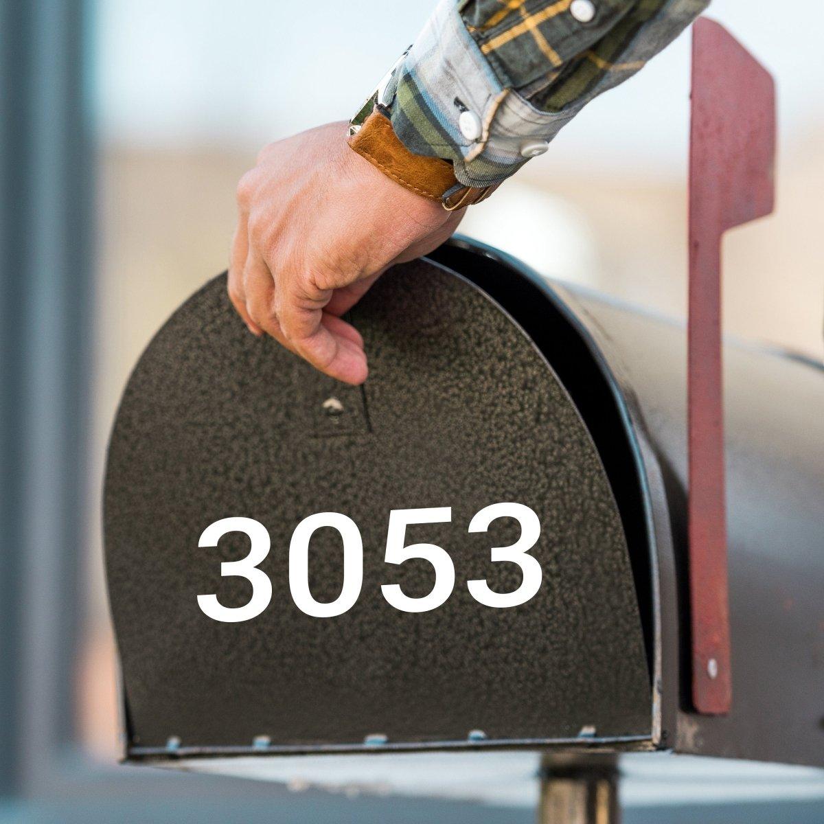 Person placing their hand on a mailbox displaying the number 3053, highlighting visibility with a custom decal.