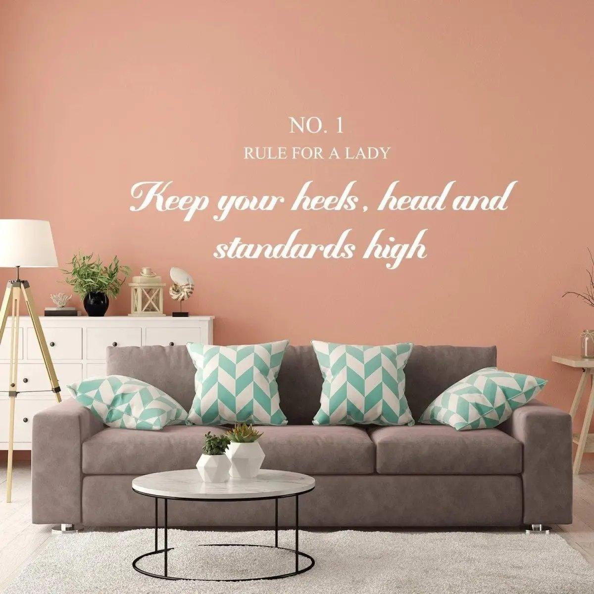 Chic wall sticker reading 'Keep your heels, head and standards high' above a stylish sofa in a modern living room.