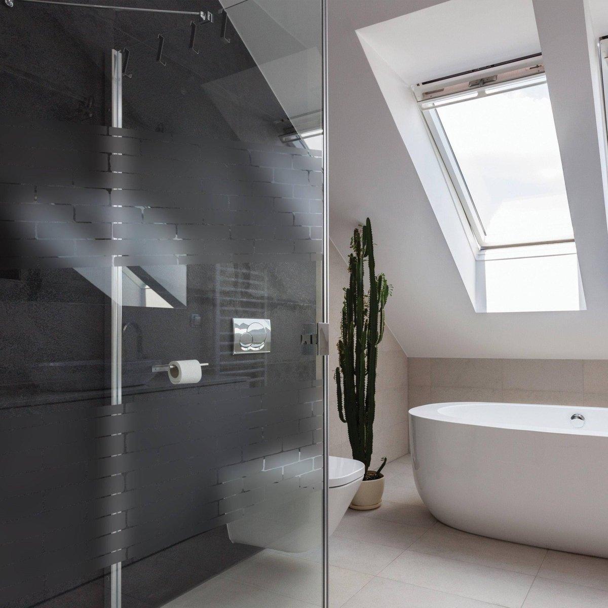 Modern bathroom featuring frosted window film, sleek shower, large bathtub, and natural light from skylight.