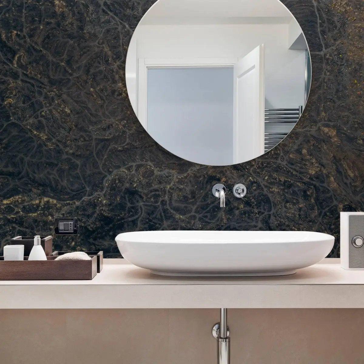 Modern bathroom with round mirror and marble effect wall covering, featuring a stylish sink and accessories.