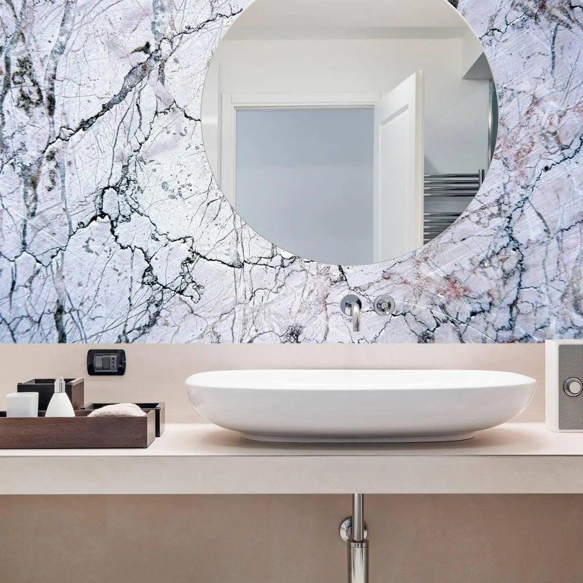 Elegant marble wall covering in modern bathroom with round mirror and stylish sink.