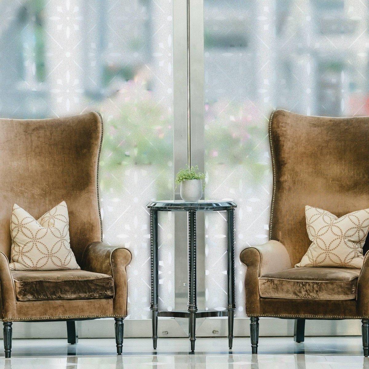 Cozy seating area with brown high-back chairs and a side table, enhanced by a frosted window decal for privacy.