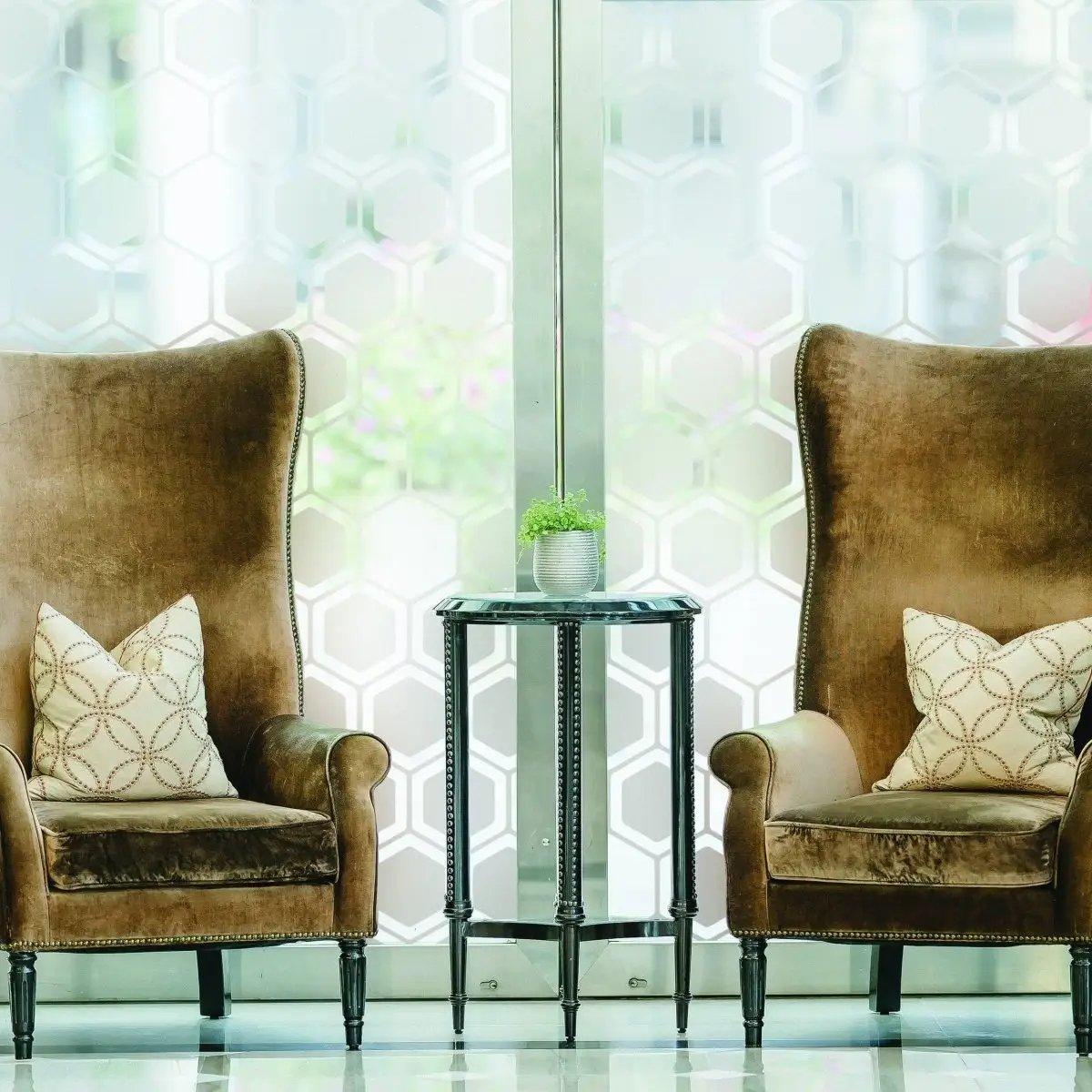 Frosted window film with hexagonal pattern behind stylish brown chairs and a side table.