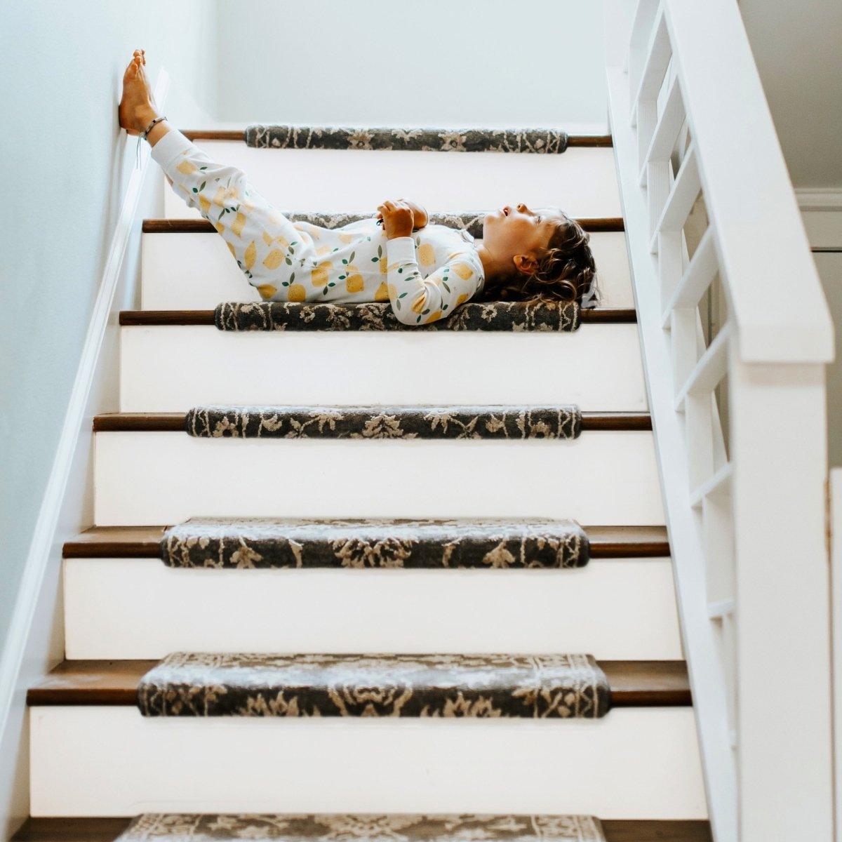 Child laying on decorated stairs with plush stair runner, showcasing a cozy home environment.