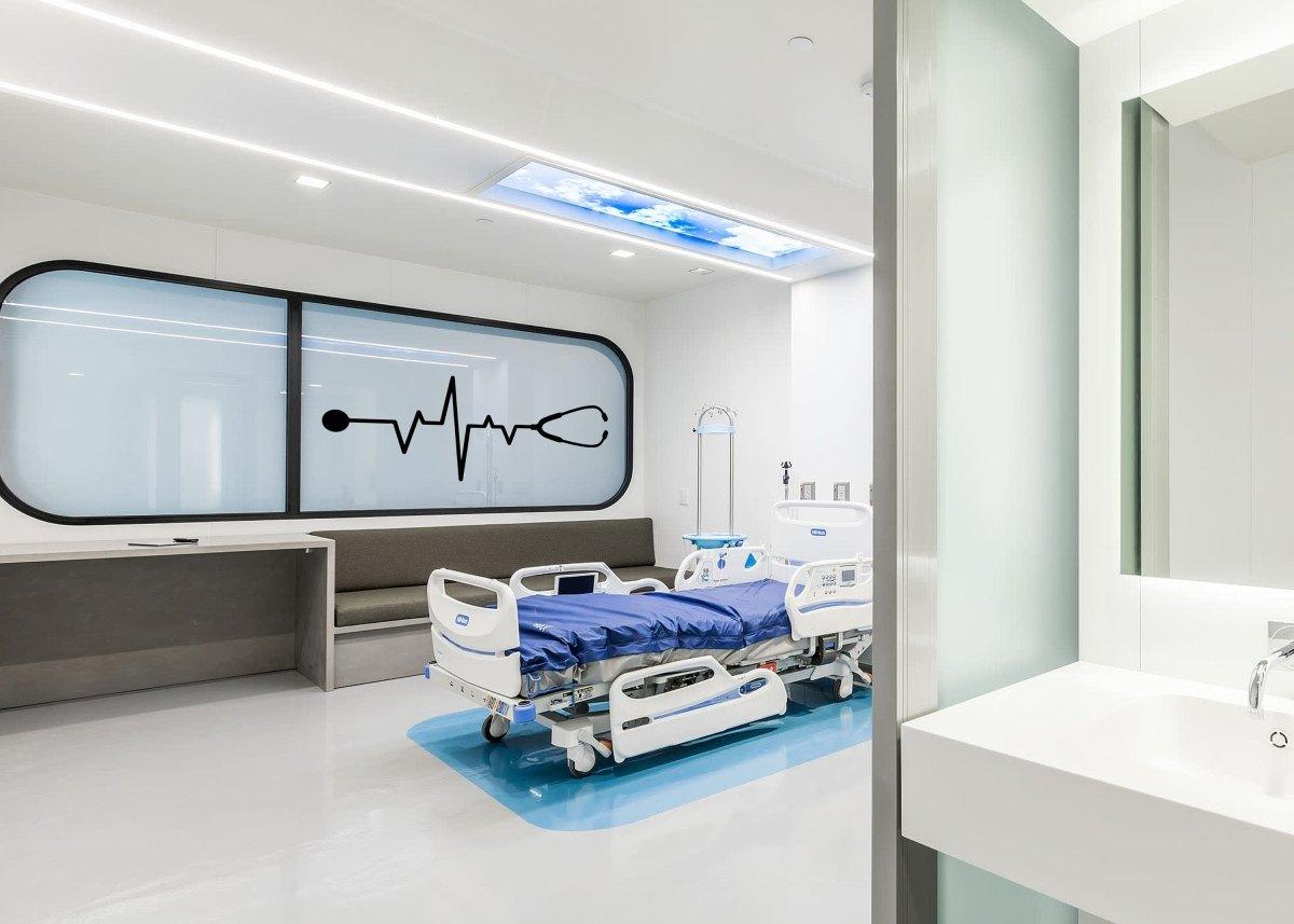 Modern hospital room featuring a patient bed and a wall decal with a stethoscope and heartbeat line.