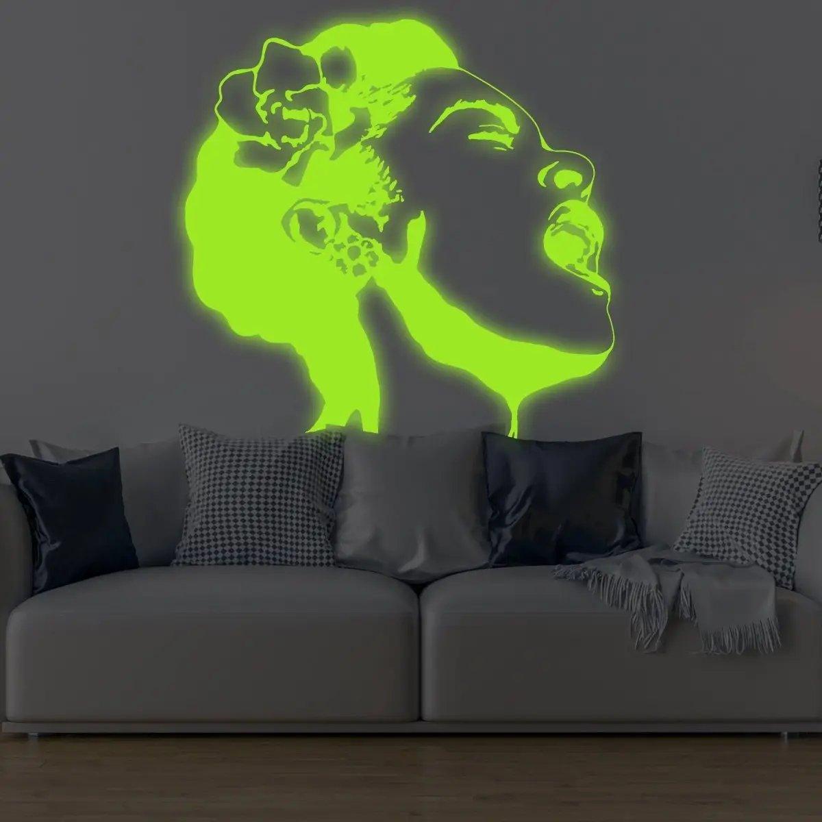 Glow in the dark wall sticker of a woman's face emitting vibrant light above a stylish sofa.