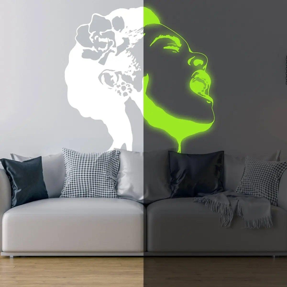 EnchantGlow luminous wall decal of a woman singing, glowing in the dark above a modern gray sofa with patterned pillows.