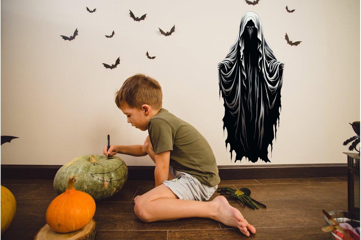 Young boy carving a pumpkin beside a spooky Halloween ghoul wall decal and bats, creating a festive atmosphere.