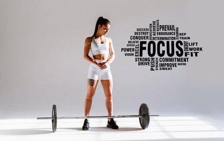 Inspirational fitness wall sticker featuring motivational words like 'FOCUS' alongside a woman with a barbell.