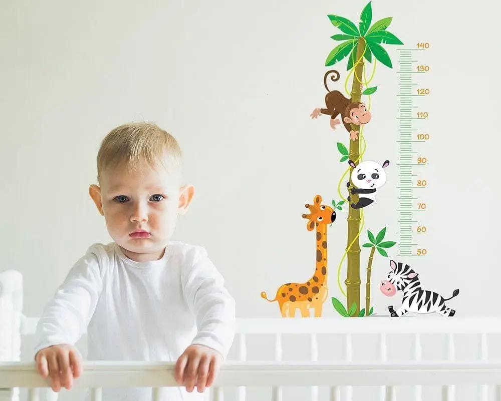 Child beside a colorful animal-themed height chart sticker, featuring a giraffe, monkey, panda, and zebra.