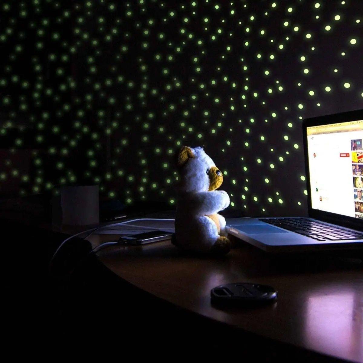 Cozy setup with a plush teddy bear watching a laptop illuminated by glowing star wall decals.