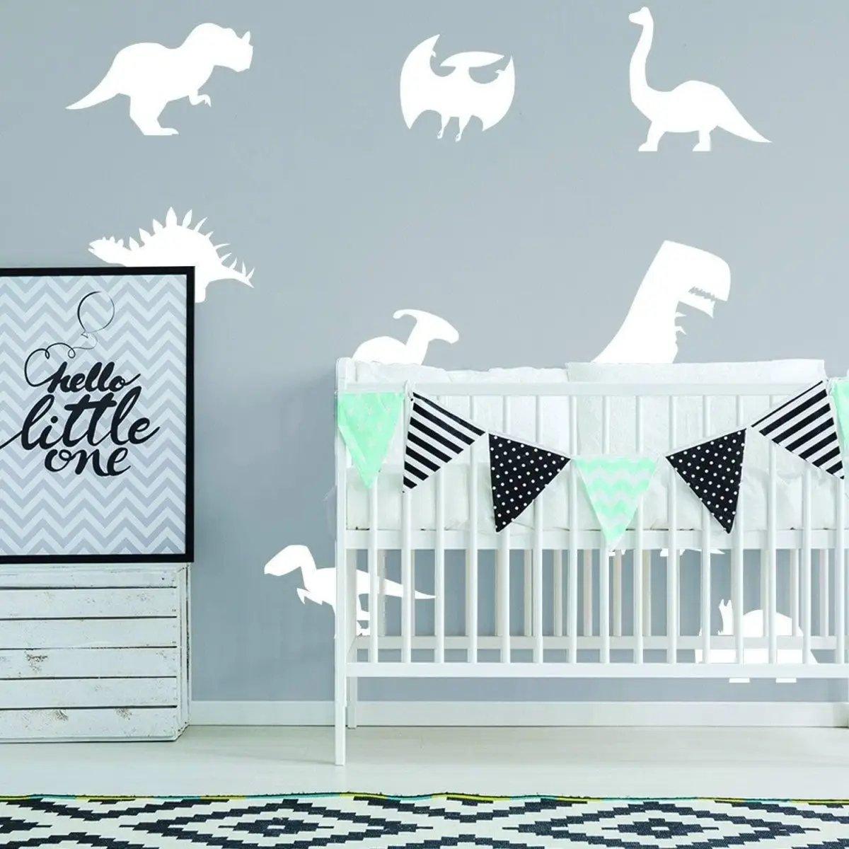 Dinosaur wall decals in a nursery, featuring various dinosaur designs above a crib with a cute banner.