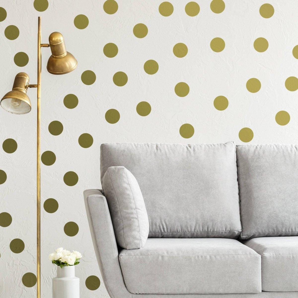 Elegant gold circle wall decals on a textured white wall behind a modern gray sofa and a stylish lamp.