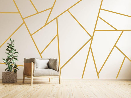 Elegant gold geometric wall stickers design with modern decor, featuring a cozy chair and potted plant.