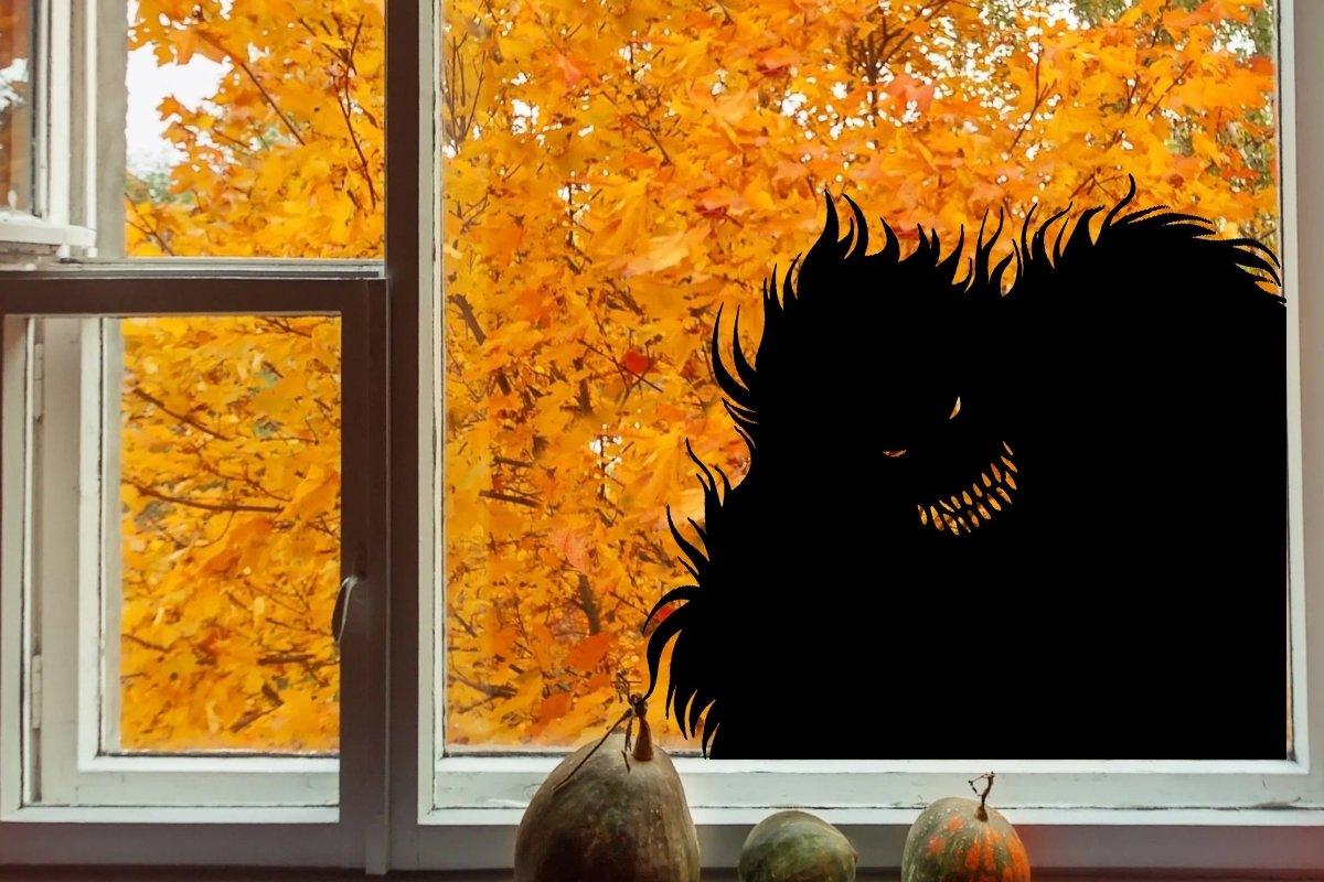 Spooky monster silhouette wall decal set against a backdrop of vibrant autumn leaves in a window.