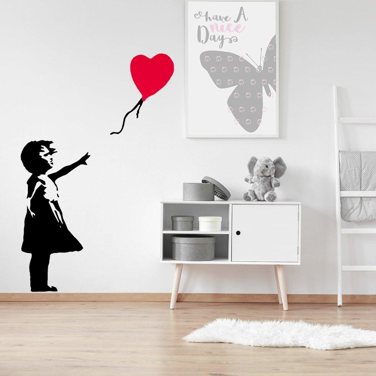 Banksy-inspired wall decal of a girl reaching for a red heart balloon, enhancing modern home decor.