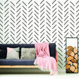 Herringbone wall stickers in black on white background with a cozy couch and decorative blanket in a stylish living room.