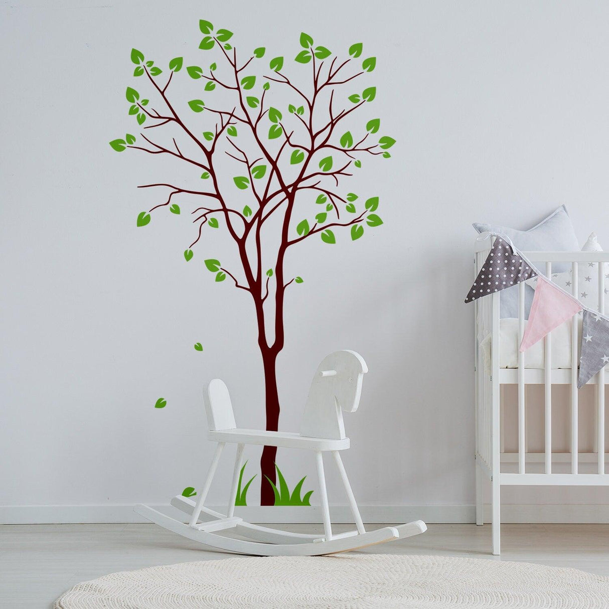 Birch tree wall decal with green leaves in a nursery, adding nature-inspired decor to the room.