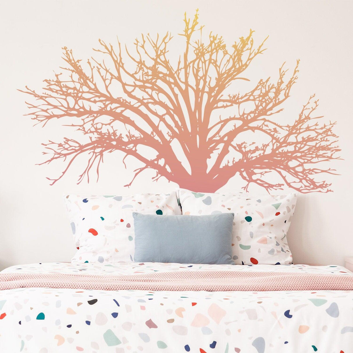 Tree sticker decal in soft colors above a bed with colorful polka dot bedding, adding a nature-inspired touch to the room.