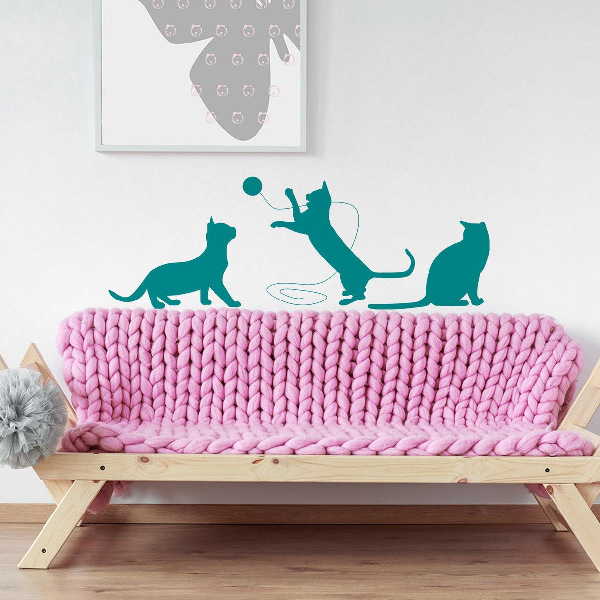 Colorful cat wall decals above a cozy pink knitted sofa in a stylish interior setting.