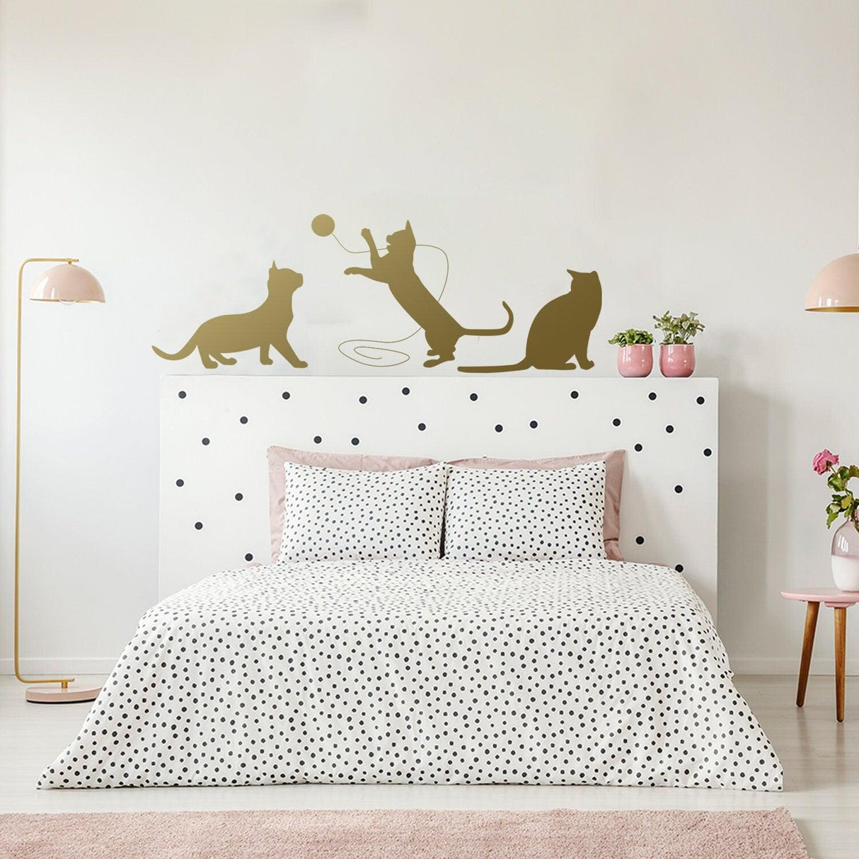 Decorative wall decal of playful cats above a bed with polka dot bedding in a stylish bedroom.