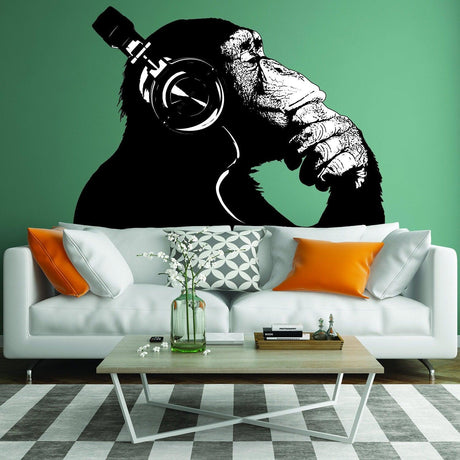 Banksy wall decal of a thoughtful monkey wearing headphones in stylish living room setting.