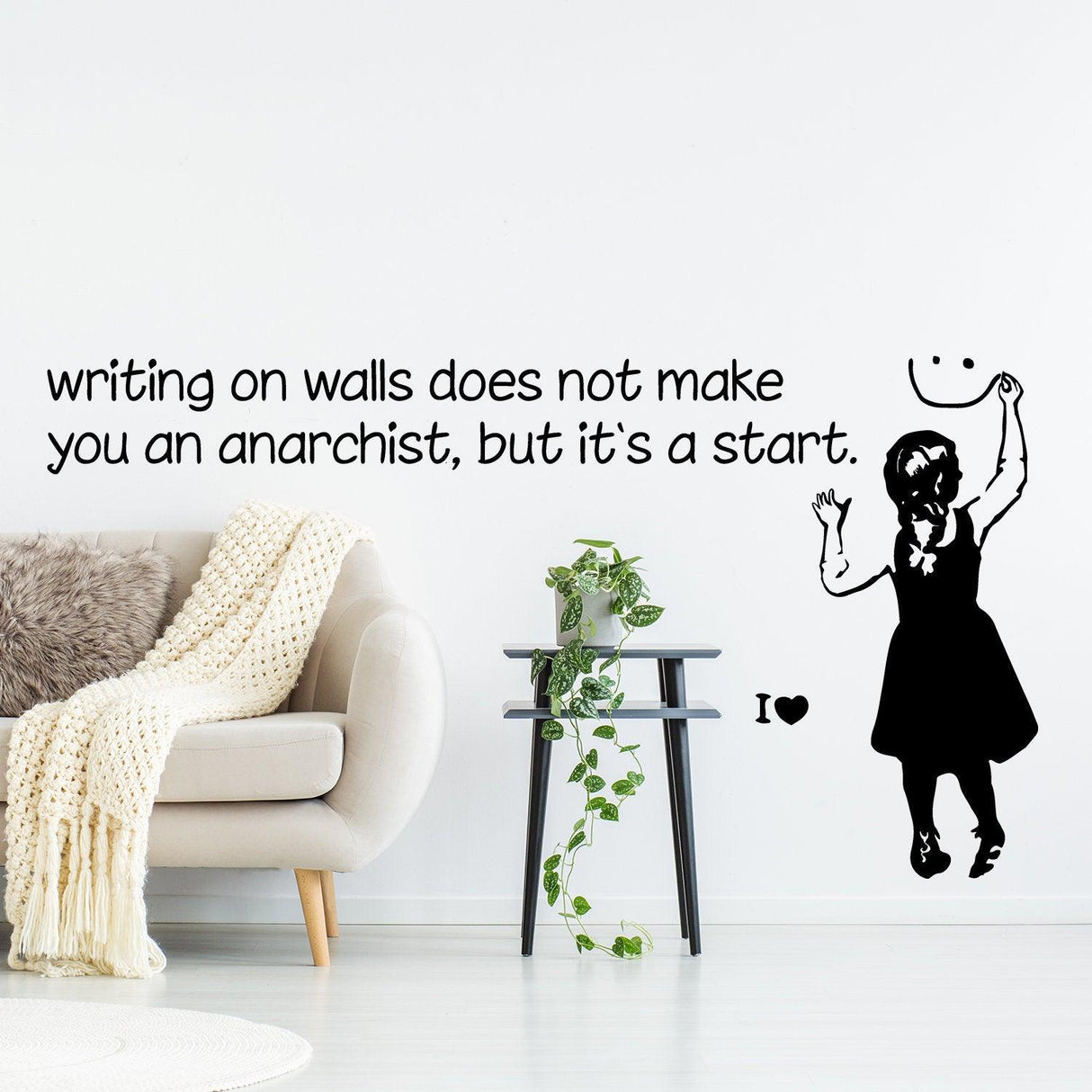 Banksy-inspired wall sticker with playful anarchist message in modern interior design setting.