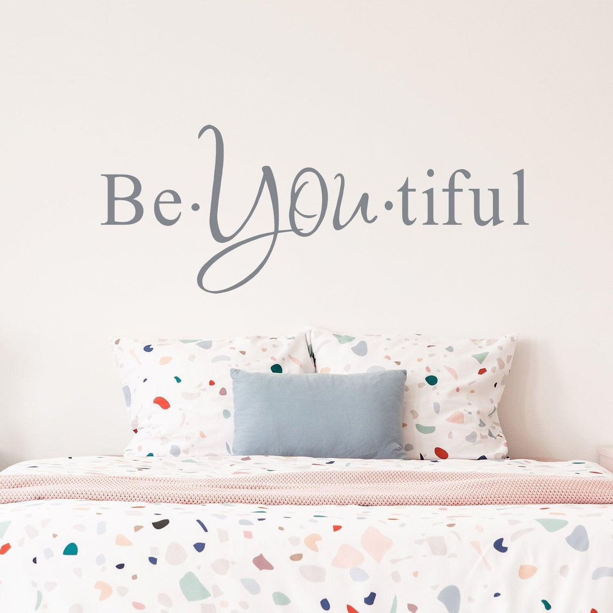 Beautiful wall sticker saying 'Be YOUtiful' above a colorful bedspread, adding inspiration to the bedroom decor.