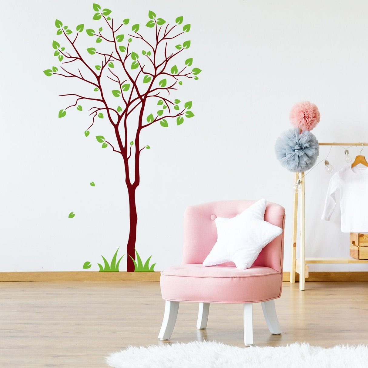Wall decal of a colorful tree with leaves in a nursery setting, featuring a pink chair and decorative elements.
