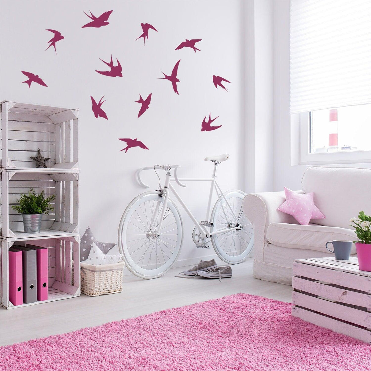 12x flock of birds wall stickers in pink on white wall, bright living room decor with bicycle and pink rug.