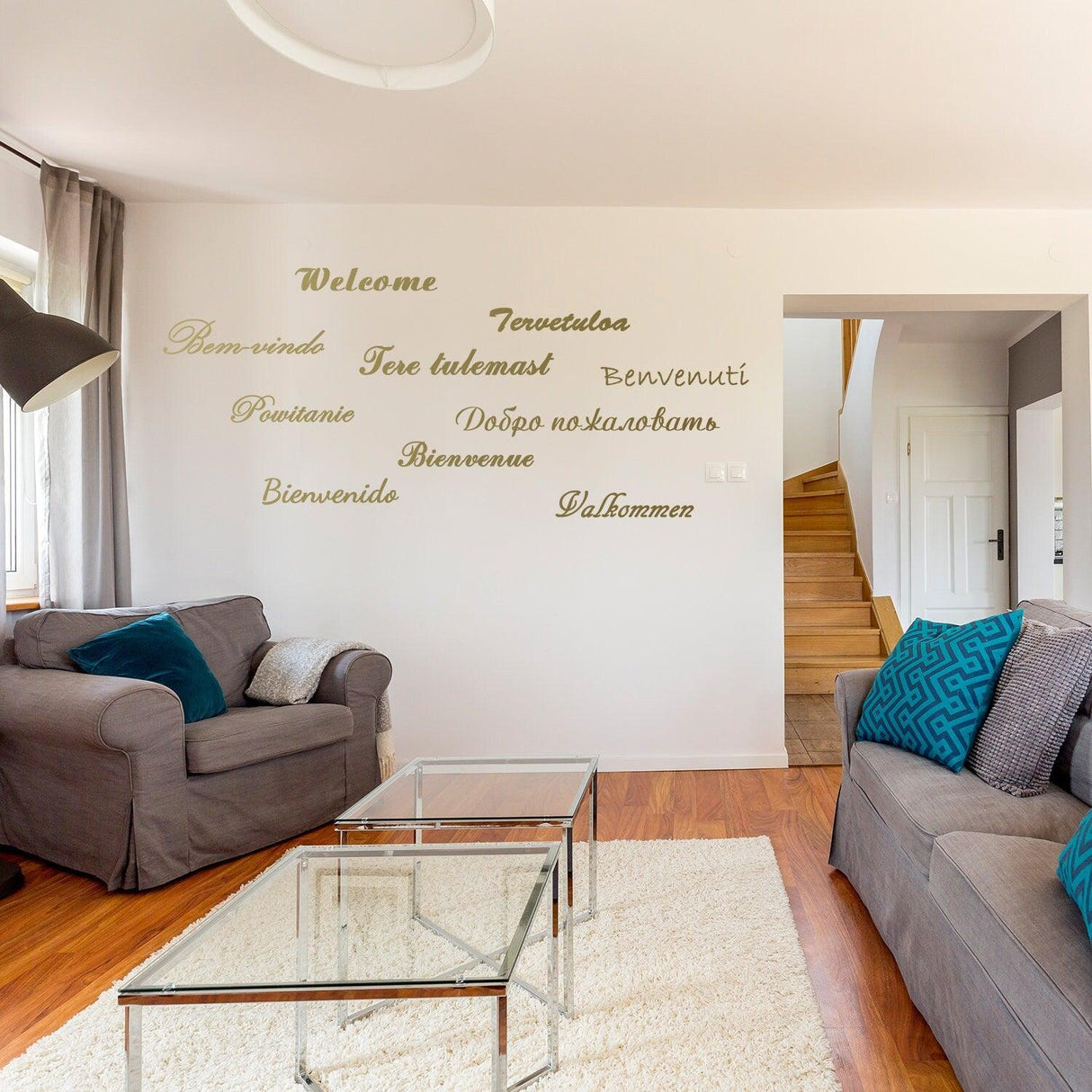 Vinyl wall stickers displaying 'Welcome' in multiple languages on a living room wall.
