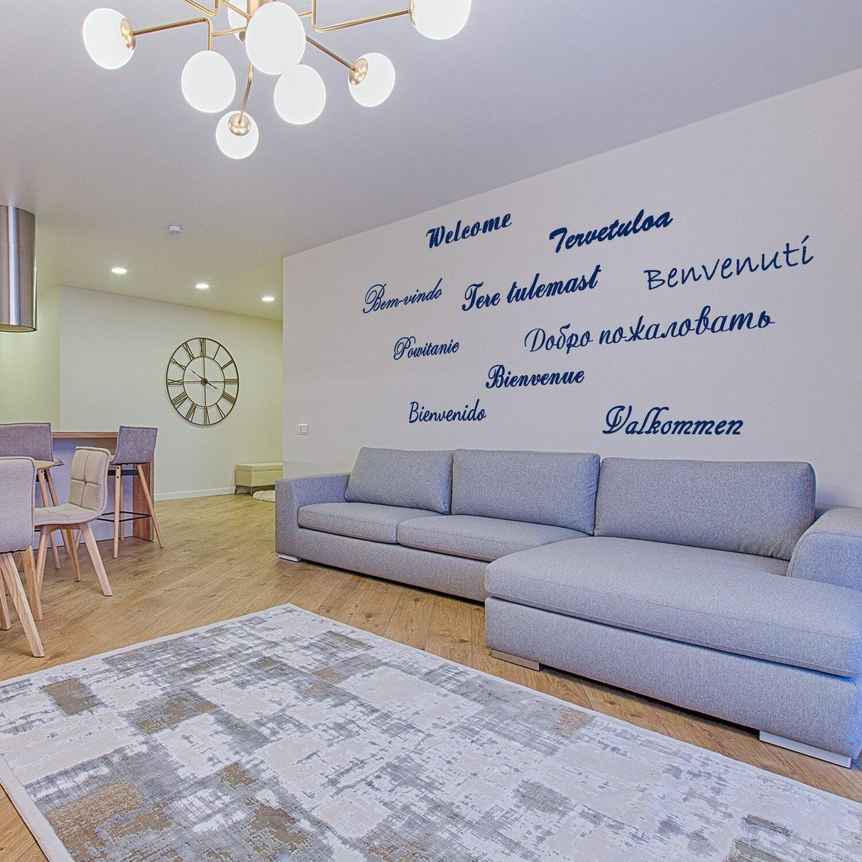 Living room featuring a stylish wall decal with 'Welcome' in multiple languages, cozy sofa, and modern decor.