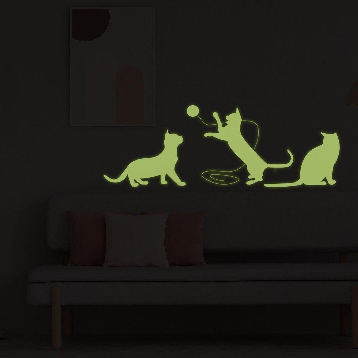 Glow in dark vinyl cat wall sticker featuring playful kittens in silhouette on wall above sofa.