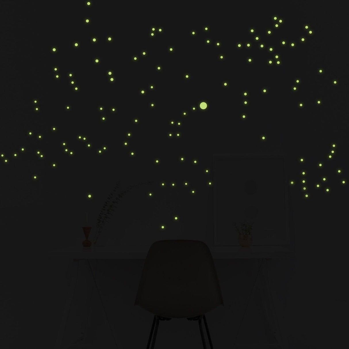 Glow in the dark star wall stickers creating celestial constellations in a dark room above a desk.