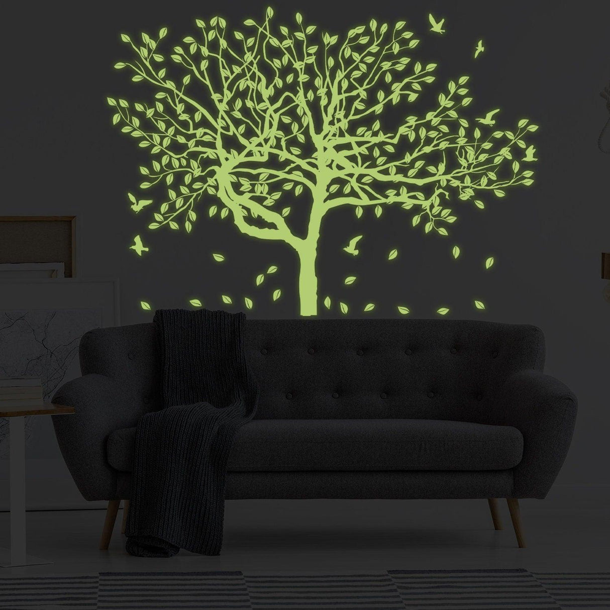 Glow in the dark tree wall sticker with leaves and birds, illuminating a cozy living room setting.