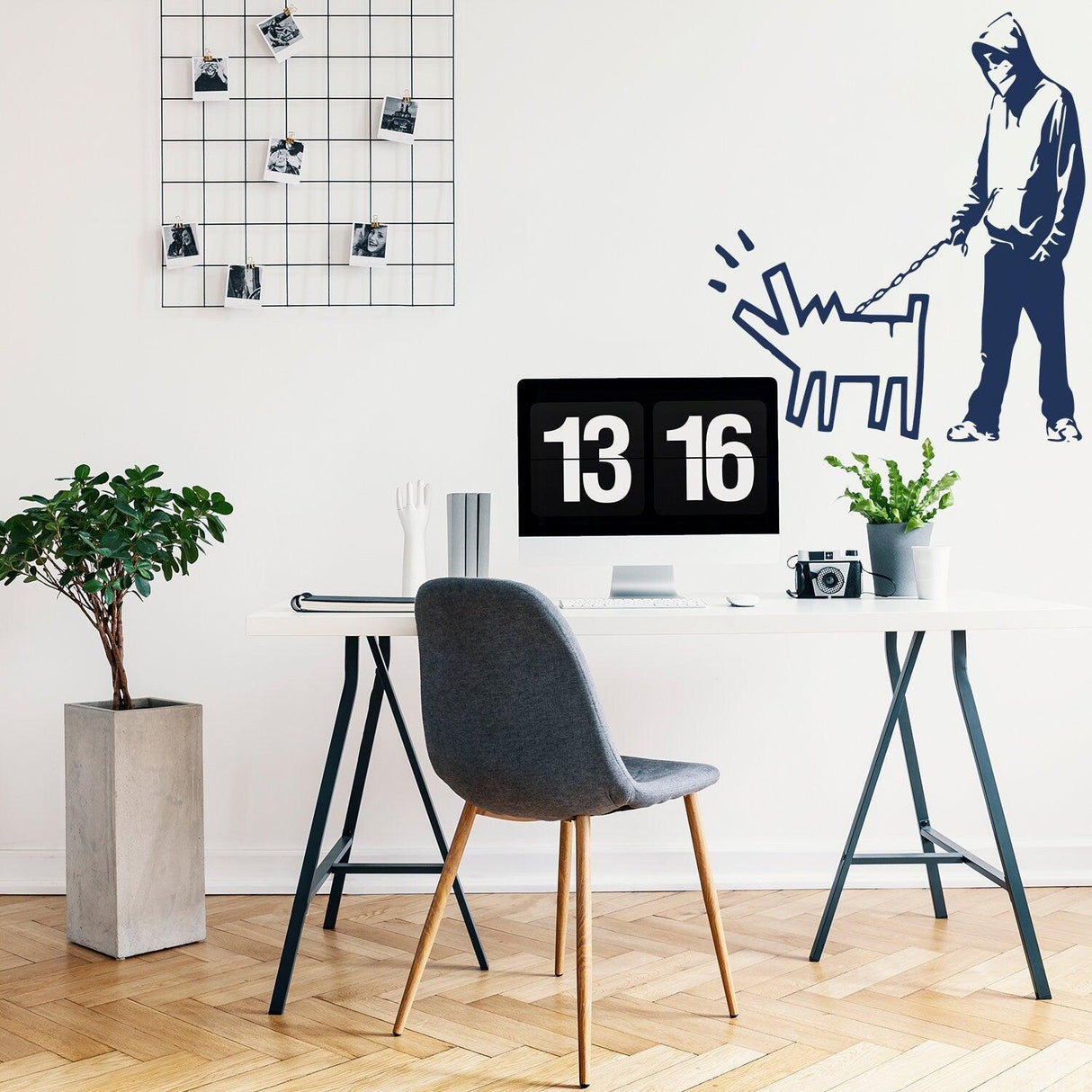 Banksy-inspired wall sticker of person walking dog in modern office decor with plant and computer setup.