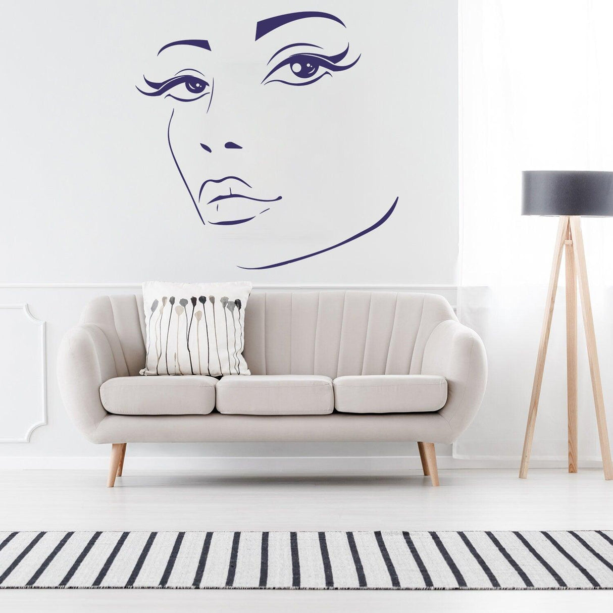 Woman face black wall vinyl sticker above a stylish sofa in a modern living room, showcasing beauty art decor.