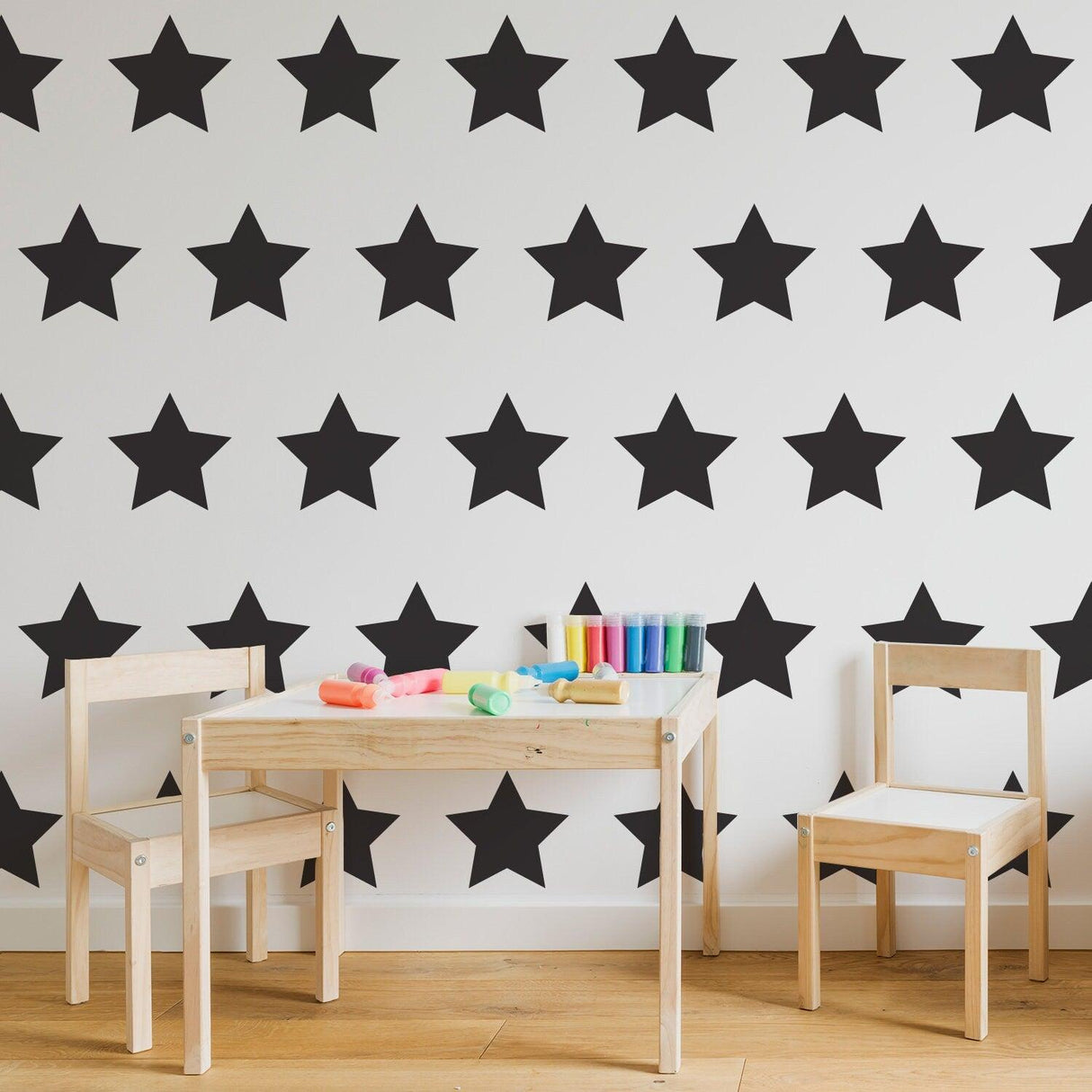 Black star wall stickers in a baby room with a wooden table and chairs, perfect for baby shower decor.